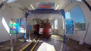Fishbowl view from inside the car wash, of a white SUV being washed