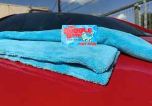 A Bubble Bath car wash gift card on a blue towel, sitting on a shiny red car